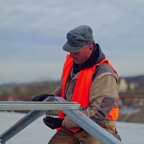 worker attaches metal basis for solar panels. installation of a new solar energy farm on a flat roof of a building.