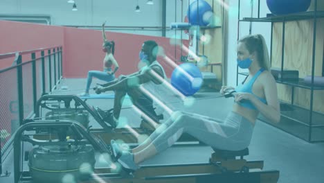 estructura de adn girando contra mujer caucásica con máscara facial haciendo ejercicio de remo en el gimnasio