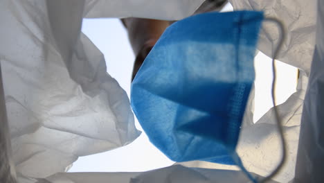 man throws used face mask into the waste bin