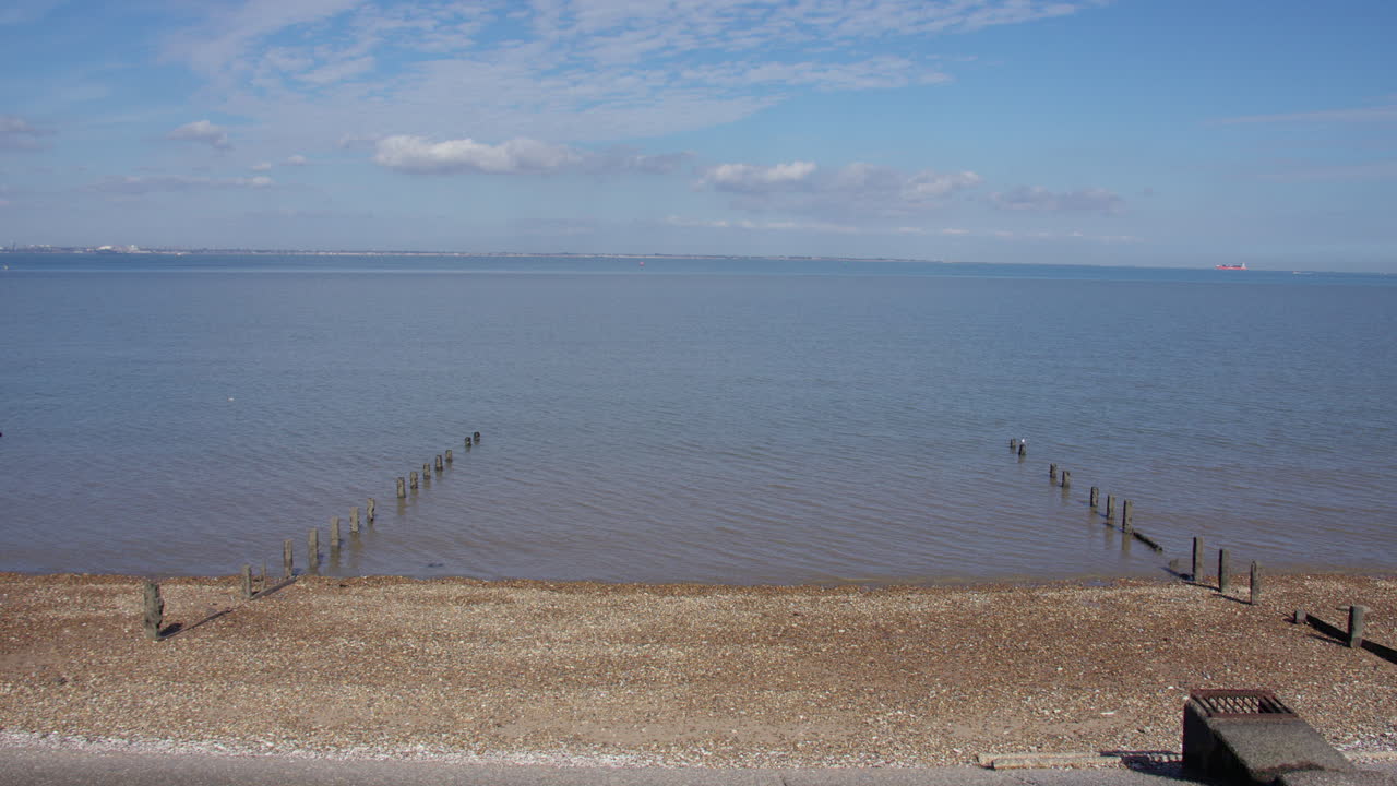 Bidikan lebar Pantai Sheerness dengan dua pemecah gelombang, dengan muara Sungai Thames di latar belakang
