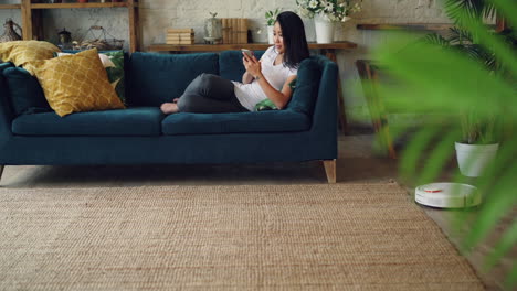 mujer relajándose en el sofá usando un teléfono inteligente