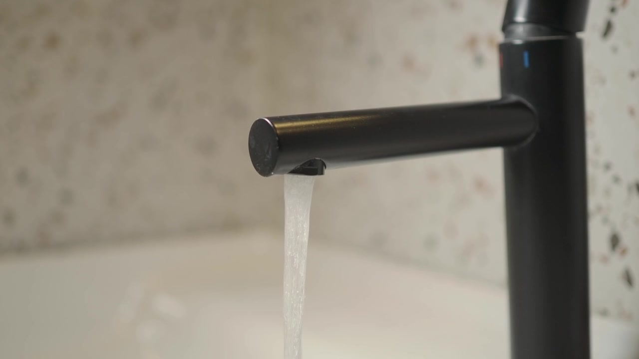 Primo piano di acqua che scorre da un moderno rubinetto nero