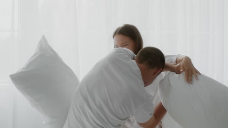 couple having a pillow fight in bed