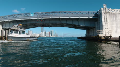 Vista-Desde-Una-Pequeña-Embarcación-Pasando-Un-Remolcador-Debajo-De-Un-Puente-En-Miami,-Florida,-En-Un-Hermoso-Día-De-Verano