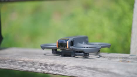 female hand put compact fpv drone on outdoor wooden bench, czech republic