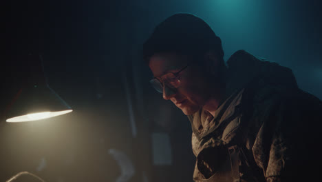 a bombmaker assembles a bomb in his workshop at night