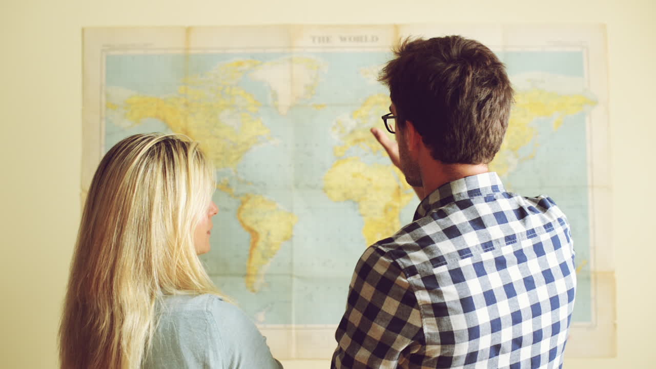 una joven pareja de turistas mirando el mapa del mundo