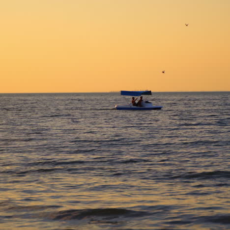 catamaran on sea background at sunset. men sailing in a blue catamaran on sea in the evening.