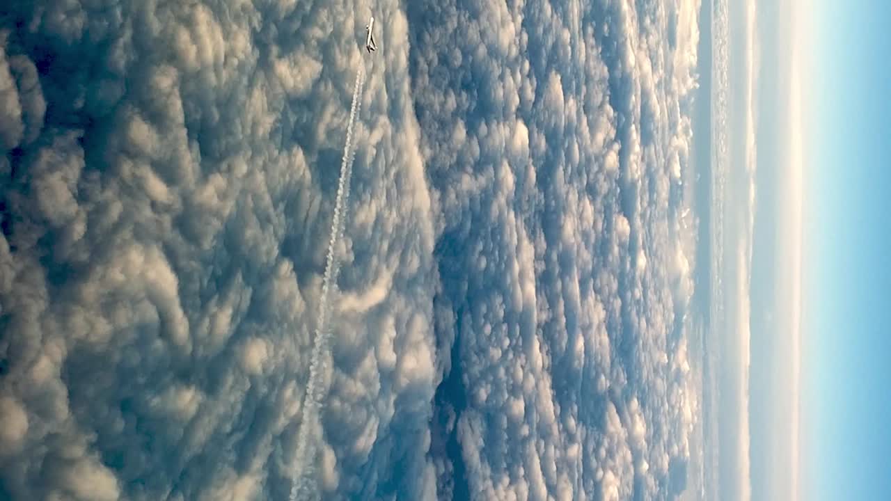 푸른 하늘에 길고 하얀 응결 증기 공기 흔적을 남기는 구름 위를 나는 비행기의 높은 각도 pov