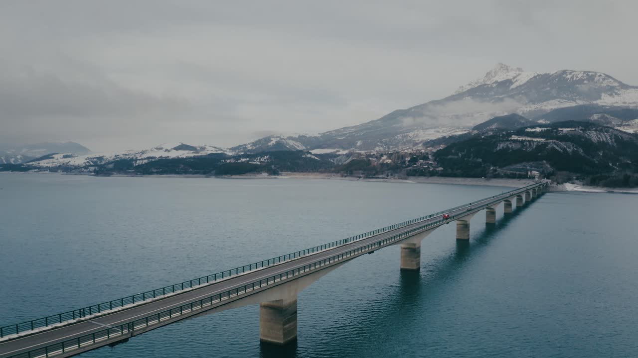 Panorama aereo del ponte di Savines sul lago di Serre-Ponçon nelle Alpi francesi in una giornata nuvolosa.