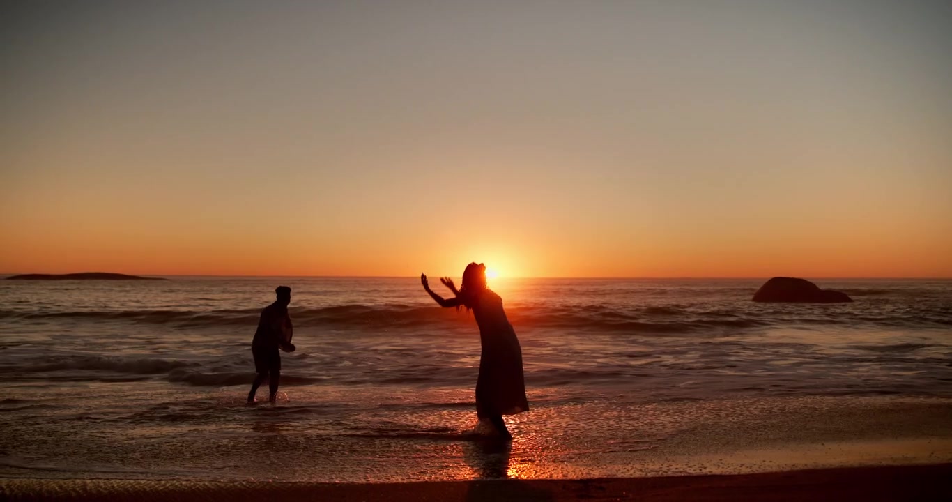 Couple Playing in Ocean Waves at Sunset