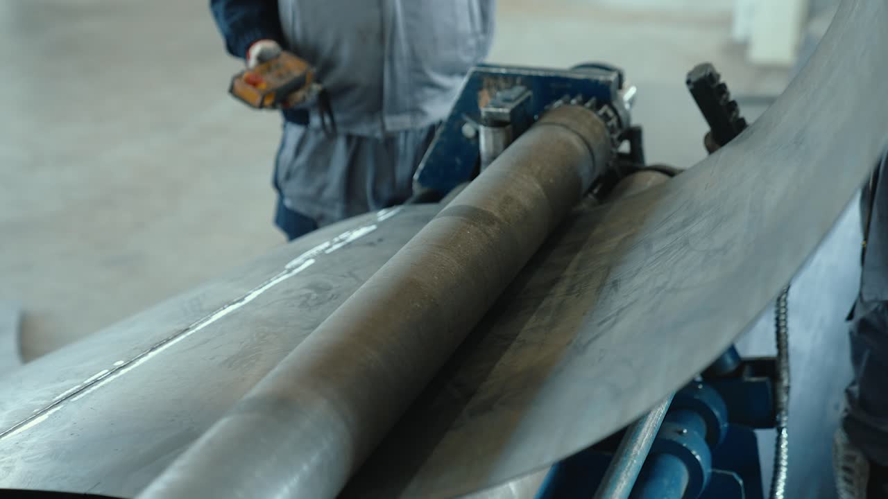 Passing a sheet of metal through a round shaft. Metal rolling machine working in industrial workshop