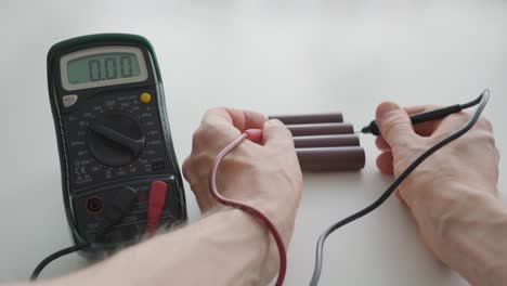 man using a multimeter to measure the voltage of the batteries