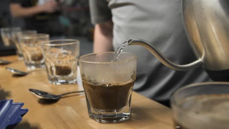 pouring hot steamy water for coffee cupping taste test, slow motion close up