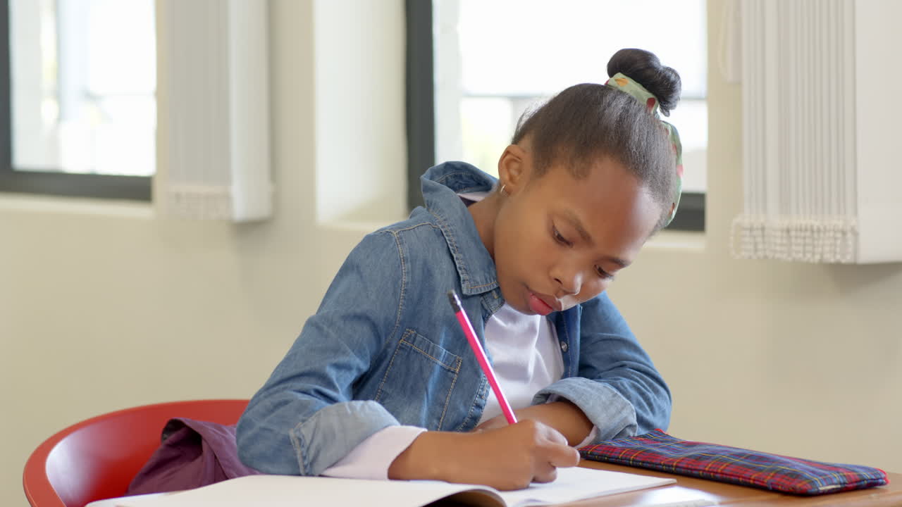 In school, young girl writing in notebook, concentrating on her studies
