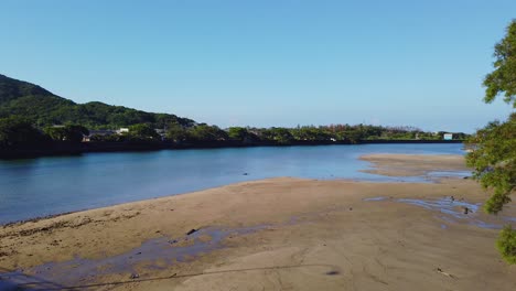 Kurio-town-and-river-flowing-into-ocean-tide-flats,-Yakushima-Japan