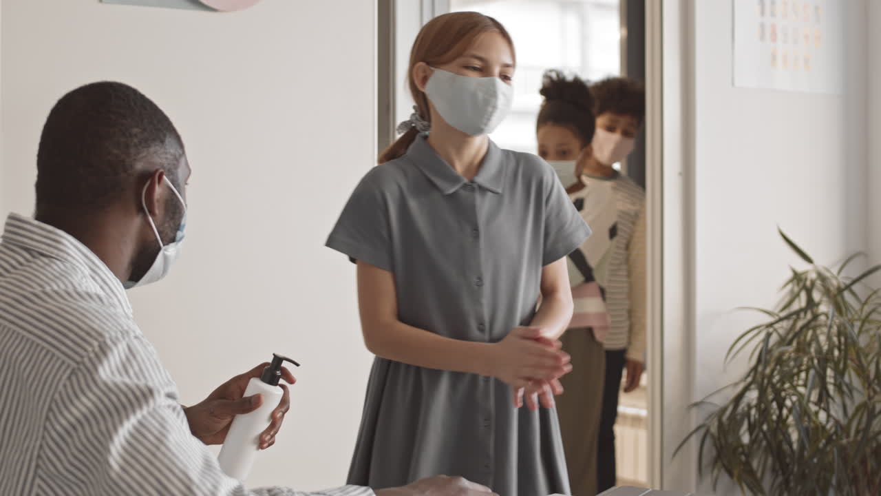 Teacher Pouring Sanitizer on Students Hands