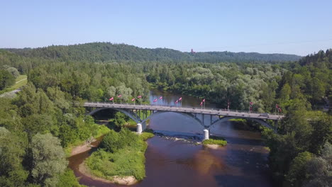 Unglaubliche-Luftaufnahme-Einer-Brücke-Und-Eines-Flusses-In-Der-Ländlichen-Landschaft-Von-Lettland