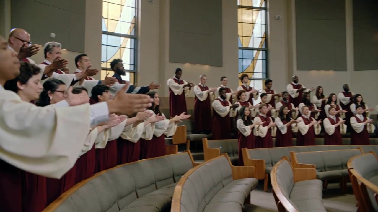 Opening note sparking maroon robes choir moving from still to clapping on church risers in worship