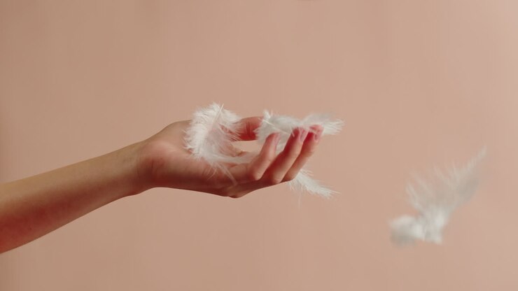 Mano di donna che afferra piume in caduta