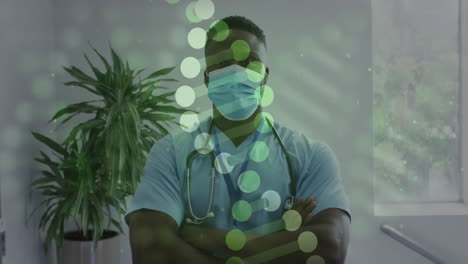 animation of dna strand over african american male doctor with arms crossed