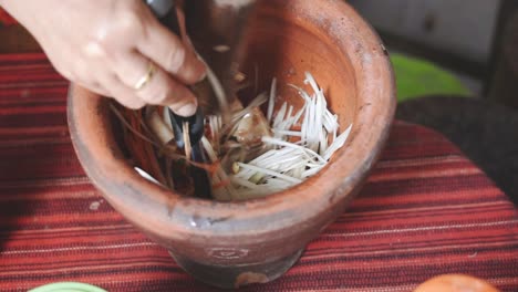 cocinando la serie som tam: la mano del vendedor de comida callejera en cámara lenta golpeando y mezclando papaya verde y zanahoria en mortero usando mortero y cucharón para hacer som tam en el restaurante de comida callejera