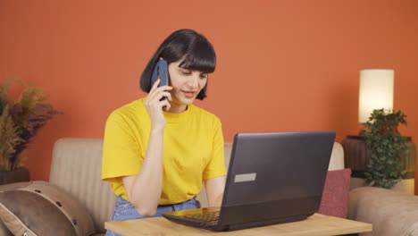 Woman-using-laptop-nervously-talking-on-the-phone.