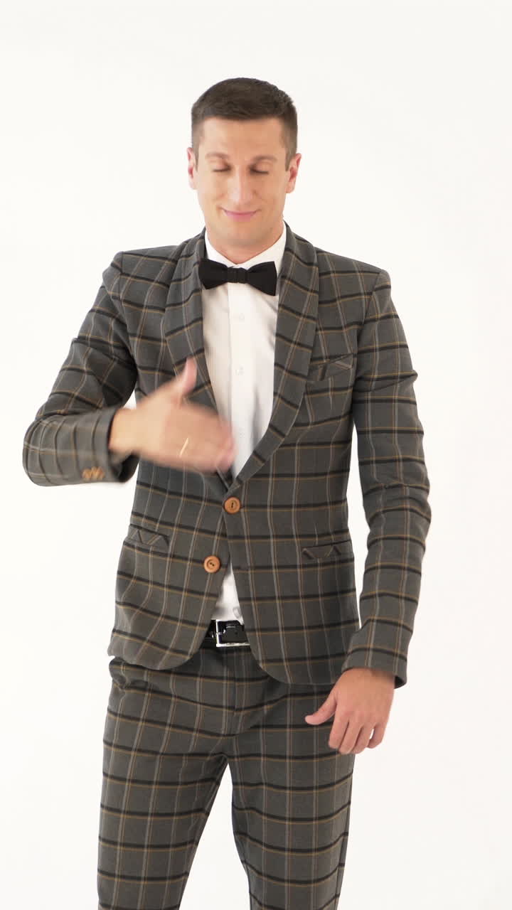 talented showman is holding his hand in front of his face and showing sad and funny emotions with his face in a white background Vertical video