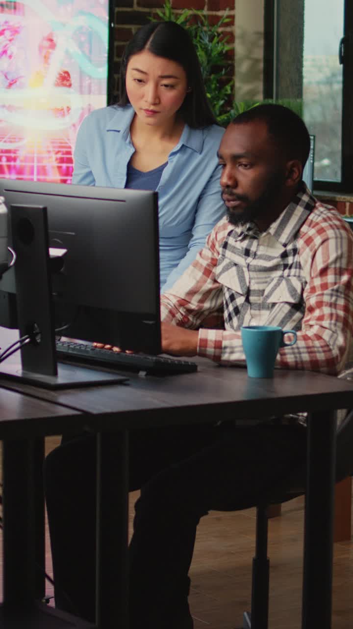 Vertical video: Creative agency employees using computers to develop new graphics interface