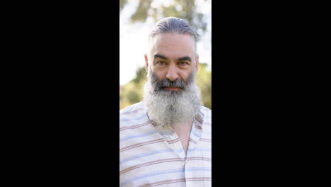 vertical video: smiling bearded man outdoors, enjoying sunny day in casual attire