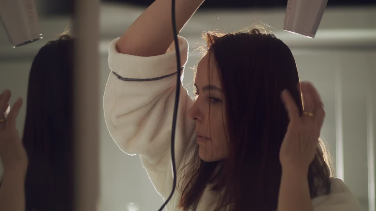 그녀는 그녀의 왼손으로 그녀의 머리를 괴롭히는 동안 그녀의 머리 위에 타격 건조기를 들고 여자