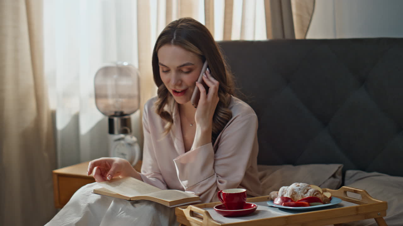 Woman talking on the phone while having breakfast in bed