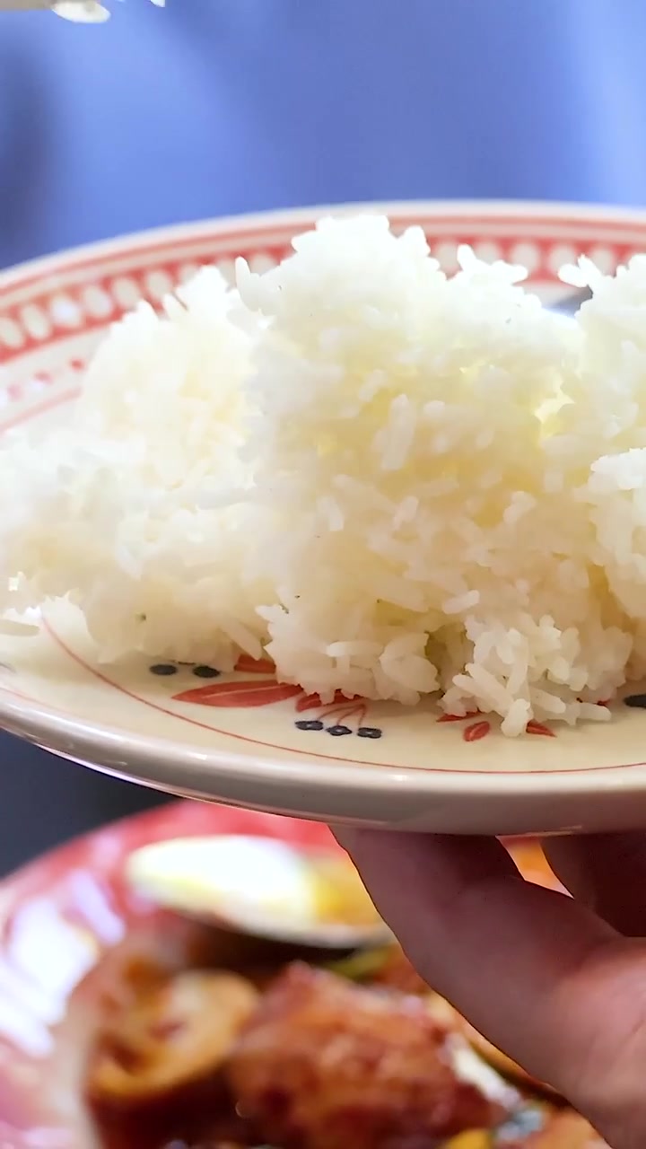タイの共同食事会で、皿にご飯を盛り付ける手