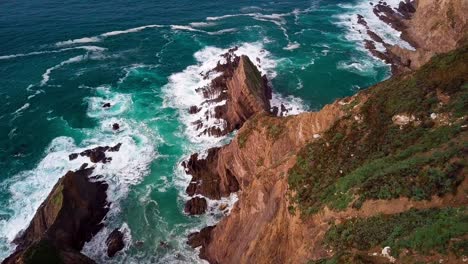 flying down huge rock cliff with breaking ocean waves in big sur, cali