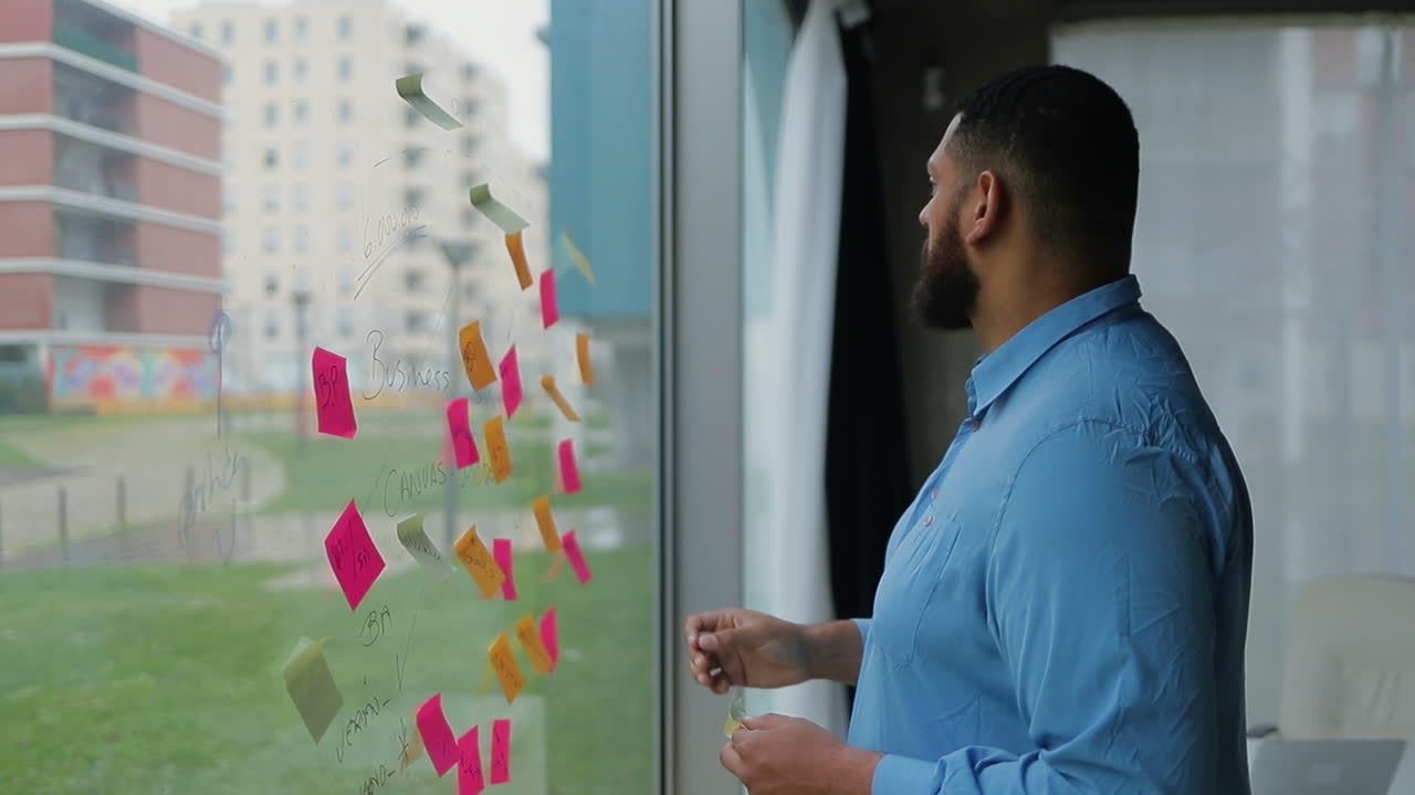 hombre barbudo enfocado cambiando el plan de negocios escrito en la ventana