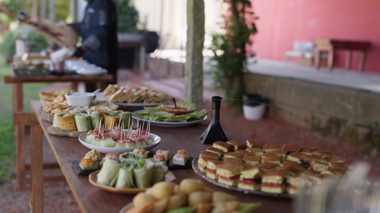 Tavolo da buffet con mini tramezzini, involtini, tartine e spiedini allestito all'aperto per un evento