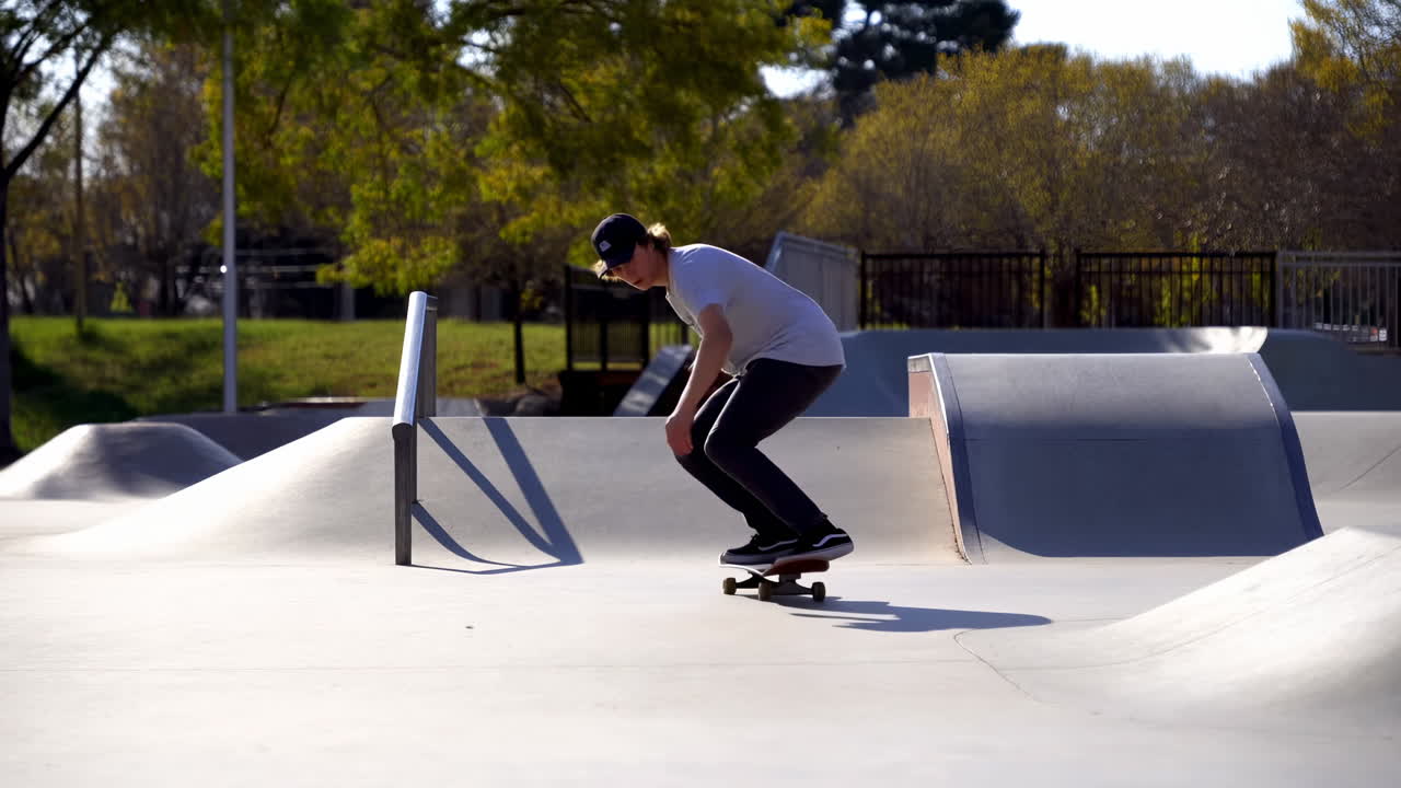 Giovane uomo che fa skateboard ed esegue un trick in uno skatepark soleggiato