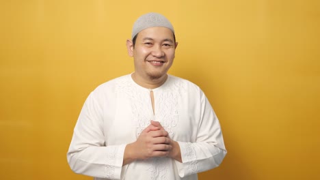 행복 한 젊은 아시아 무슬림 남성 의 초상화 는 노란색 에 대 한 카메라 를 위해 미소 짓고 포즈 를 취 하고 있다