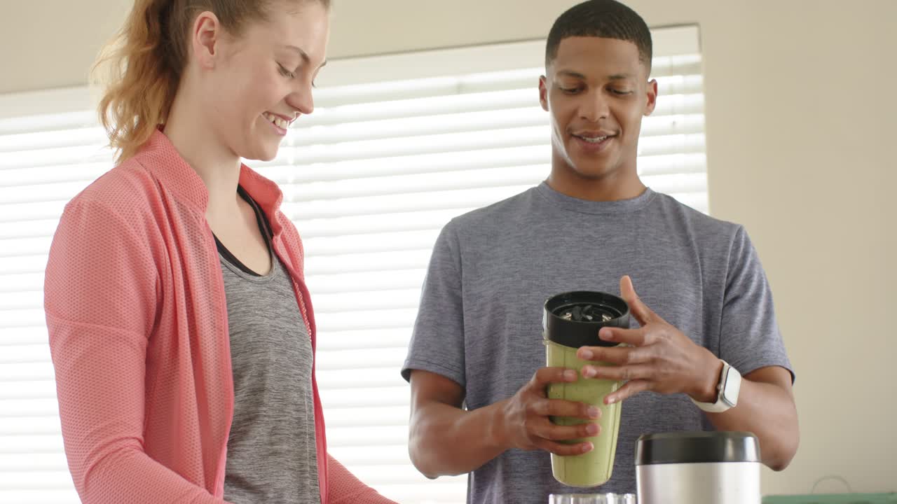 Mutfak tezgahına blender sürahisini yerleştiren, yeşil smoothie hazırlamak için kapağını çeviren farklı bir çift