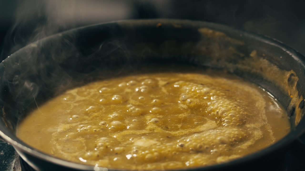 Green boiling sauce texture close-up macro. Cooking green curry with wooden spoon at home.
