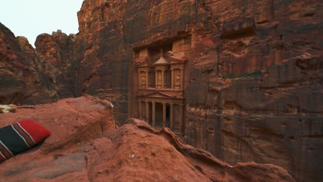 The-Treasury-at-Petra,-historic-UNESCO-heritage-site-carved-into-sandstone-in-Jordan-seen-from-above-and-sideways-valley