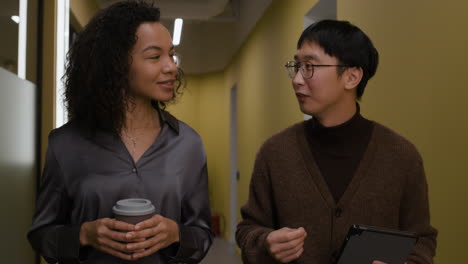 two colleagues walking and talking in hallway