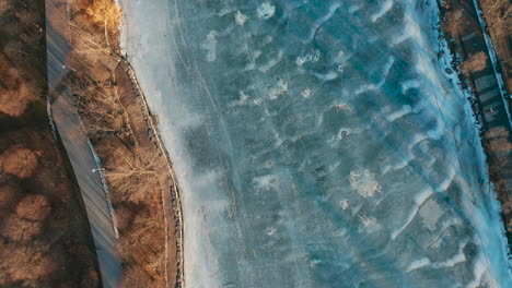 aerial shot of frozen ice blue canal by park land