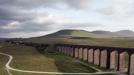 backwards aerial shot revealling ribblehead viaduct in the yorkshire dales from side on angle