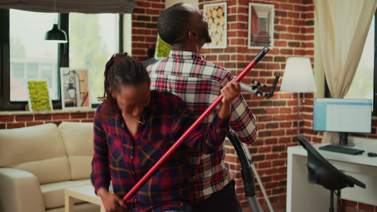 Smiling couple dancing and cleaning apartment with music