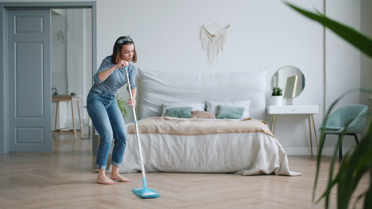 Woman happily mopping the bedroom floor
