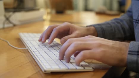 male hands typing on keyboard in office environment, slow motion