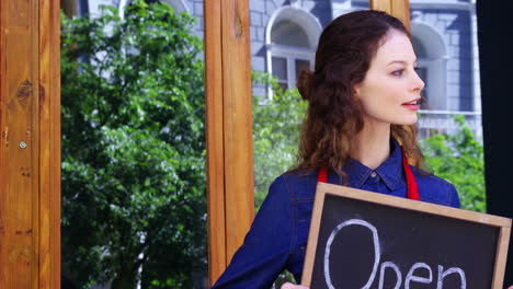 smiling waitresses holding open sign board