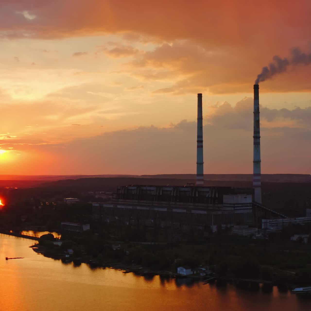 Industrial factory. Smoke comes from the chimneys of the factory, polluting the atmosphere. Video from drone on beautiful sunset