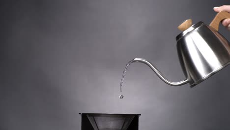 water coming out of a coffeepot pouring into a pour over coffee maker in super slow motion